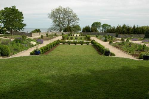 A landscaped garden with neatly arranged flower beds, pathways, and a view of the water in the background.