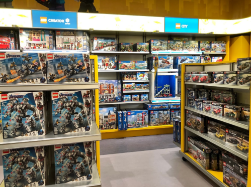 A colorful toy store aisle filled with various LEGO sets, including Avengers and City themes, displayed on shelves.