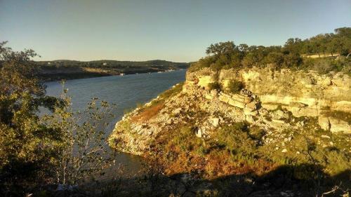 A scenic view of a river winding through rocky cliffs and lush greenery under a clear sky.