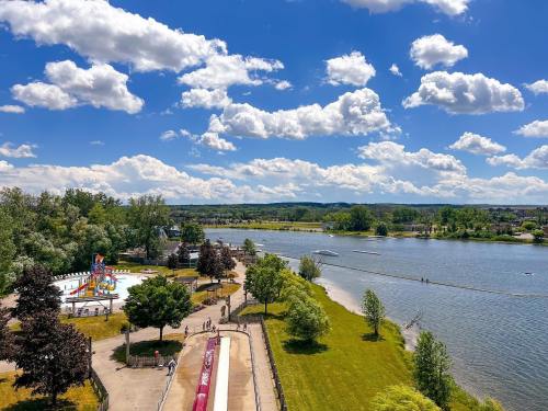 A scenic view of a river with a park, water activities, and fluffy clouds in a blue sky.