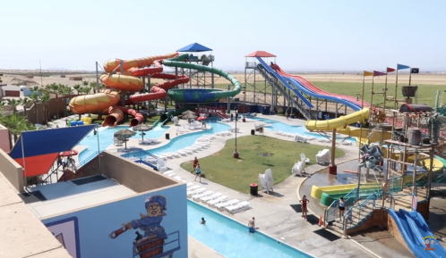 A vibrant water park featuring colorful slides, a lazy river, and families enjoying the attractions under a clear sky.