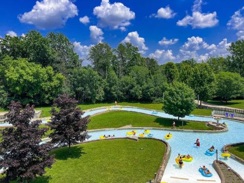A lazy river at a water park, with people floating on yellow tubes under a bright blue sky and lush green trees.