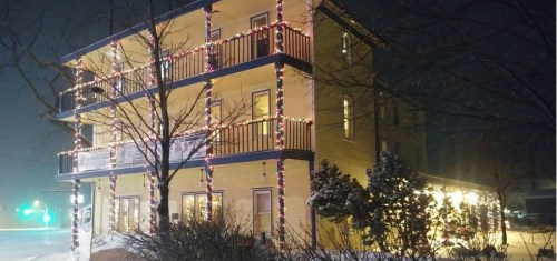 A yellow building decorated with colorful lights, surrounded by snow, on a foggy night.