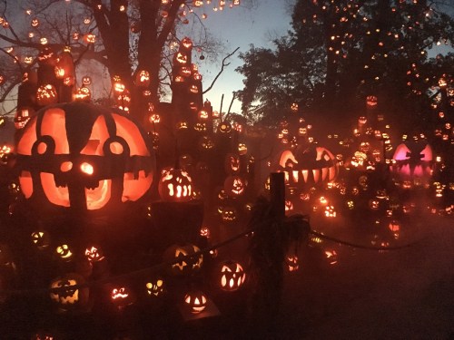 A spooky scene filled with intricately carved glowing jack-o'-lanterns against a twilight sky.