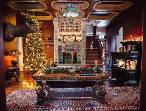 Cozy living room decorated for the holidays, featuring a Christmas tree, fireplace, and festive decor.