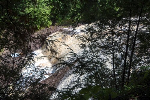 A waterfall cascading over rocks, surrounded by lush green trees and foliage.