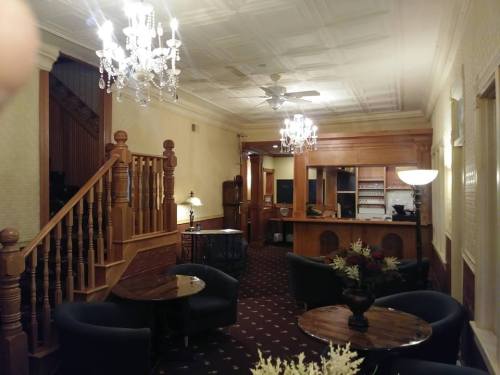 Elegant lobby with chandeliers, wooden staircase, and cozy seating areas featuring dark furniture and floral decor.