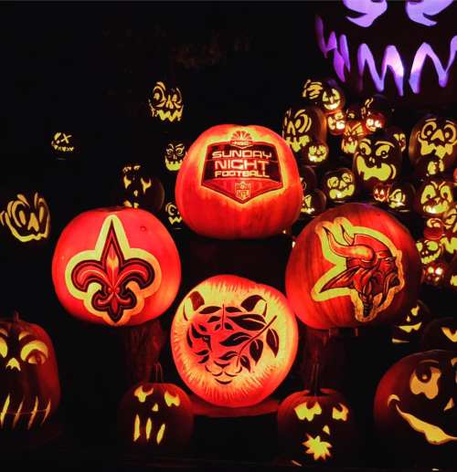 A collection of carved pumpkins glowing in orange, featuring NFL team logos and Halloween designs.