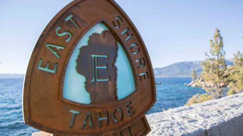 Sign marking the East Shore of Lake Tahoe, featuring a stylized "E" and scenic lake views in the background.