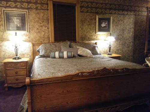 Cozy bedroom featuring a wooden bed, decorative pillows, and lamps on nightstands against patterned wallpaper.