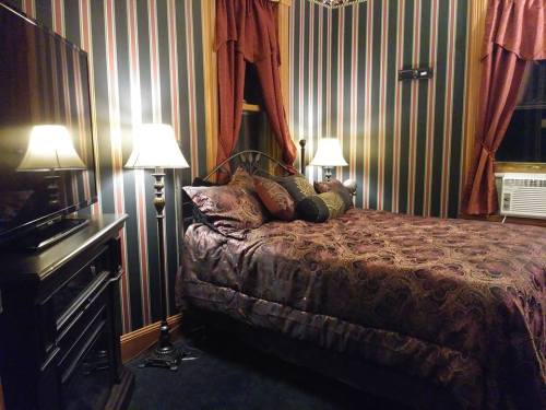 Cozy bedroom with striped wallpaper, a bed with decorative pillows, lamps, and an air conditioner.