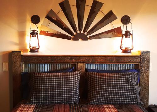 A rustic bed with plaid pillows, flanked by lanterns and a decorative sunburst headboard.