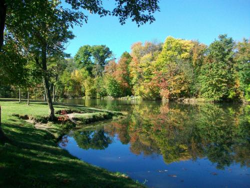 A serene lake surrounded by colorful autumn trees reflecting on the water under a clear blue sky.