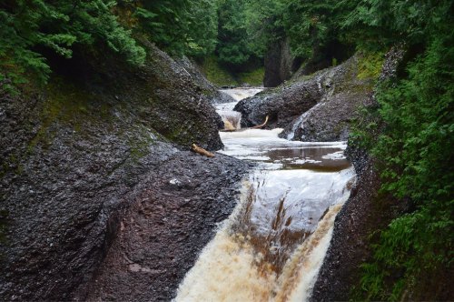 A winding river flows through rocky terrain, surrounded by lush green trees and a serene natural landscape.