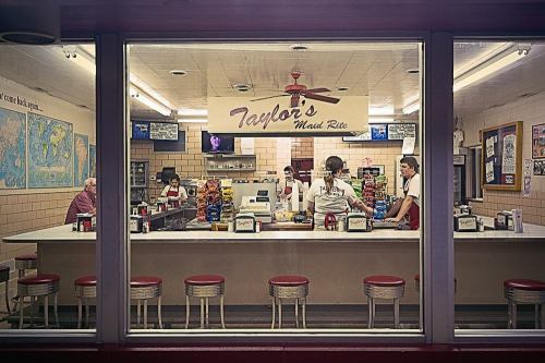 A diner interior with staff serving customers at the counter, surrounded by colorful snack bags and a welcoming atmosphere.