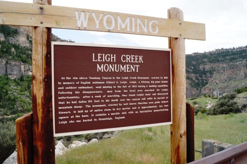 Sign for Leigh Creek Monument in Wyoming, detailing its history and significance, surrounded by mountainous landscape.