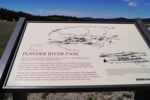 Sign at Powder River Pass, detailing its significance as the highest point on a highway in the Bighorn National Forest.