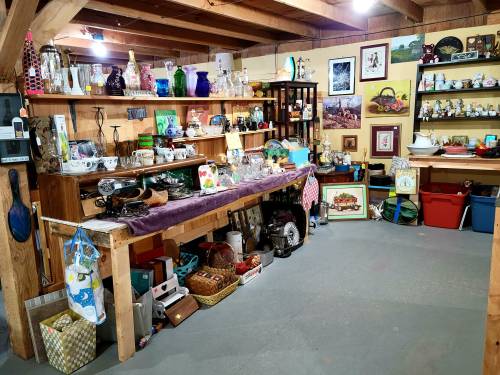 A cozy vintage shop filled with various collectibles, glassware, and decorative items on shelves and tables.