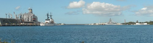 A panoramic view of a harbor with ships docked and a clear blue sky with scattered clouds.