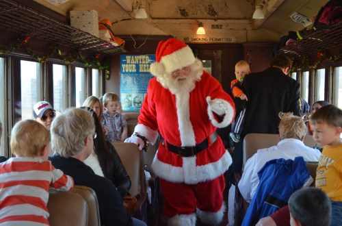 Santa Claus interacts with children and families on a festive train, creating a joyful holiday atmosphere.