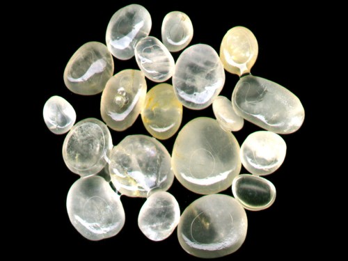 A collection of smooth, translucent stones in various shapes and sizes on a black background.