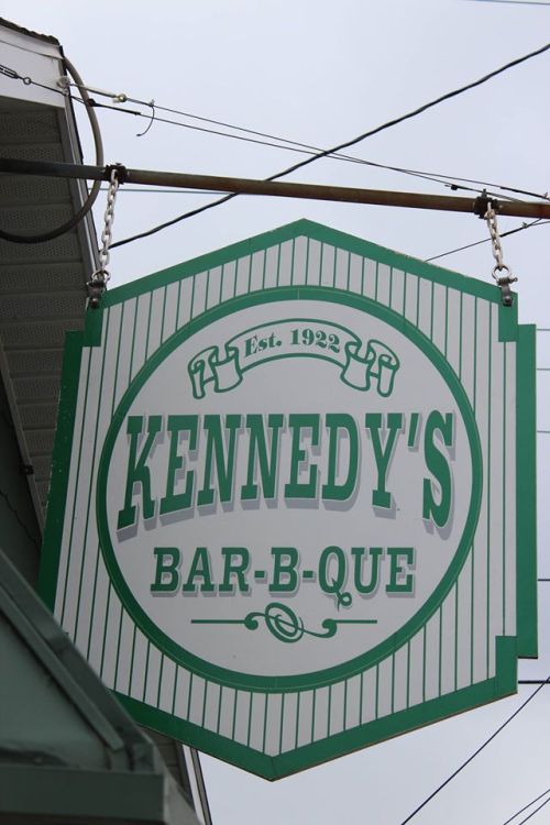 Sign for Kennedy's Bar-B-Que, established in 1922, featuring green and white colors.