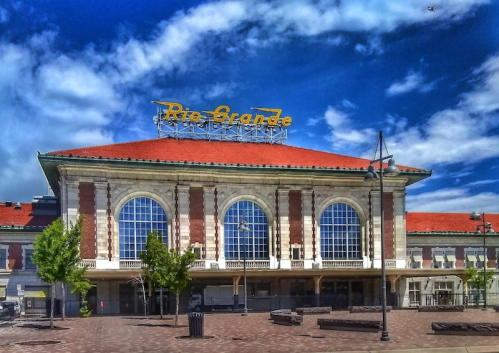 Historic train station with large windows and a bright yellow sign reading "Rio Grande" against a blue sky.