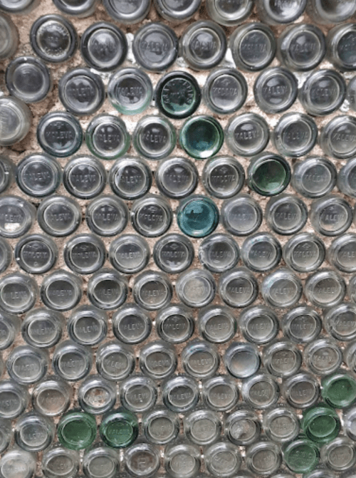 A close-up of a wall made of various glass bottle caps arranged in a grid pattern.
