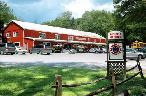 A red barn-style building with a sign reading "Butler's Orchard," surrounded by cars and greenery.