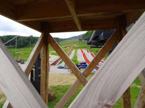 View from a wooden structure overlooking colorful water slides and a grassy area in a recreational park.