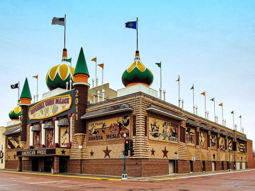 Colorful building with green and orange domes, featuring flags and murals, representing American pride.