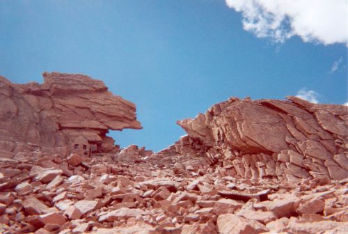 Rocky landscape with large boulders and a clear blue sky, showcasing rugged terrain and geological formations.