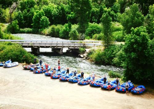 A group of people preparing to go tubing on a river, with colorful inflatable rafts lined up along the shore.