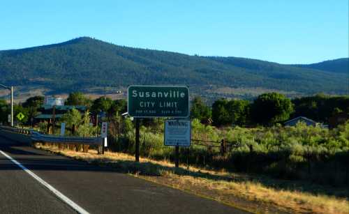 Sign marking the city limit of Susanville, with mountains and greenery in the background.