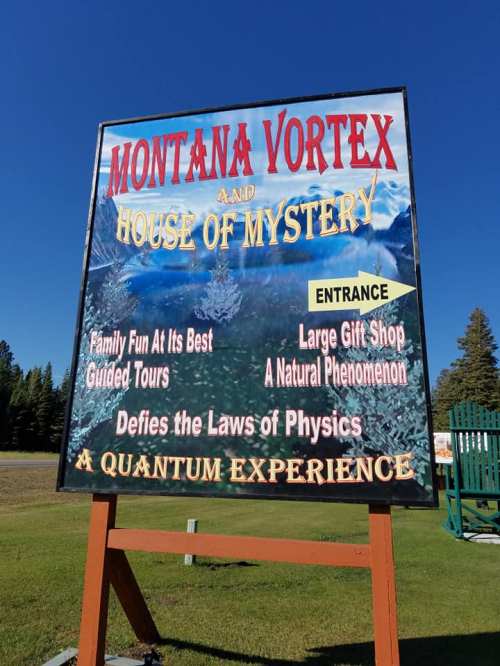 Sign for Montana Vortex and House of Mystery, promoting guided tours, a gift shop, and a unique natural phenomenon.