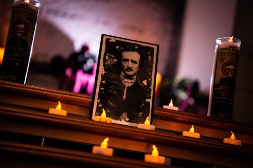 A framed portrait of Edgar Allan Poe surrounded by candles on a decorative altar.