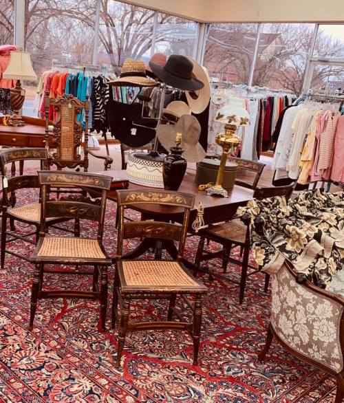 A cozy thrift store interior with vintage furniture, clothing racks, and decorative items on display.