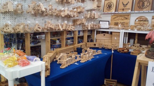 A display of various wooden crafts and toys on tables, featuring intricate designs and shapes in a shop setting.