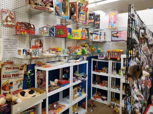 A colorful display of vintage toys and games on shelves in a store, with a sign about child supervision.