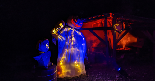 A spooky scarecrow with glowing pumpkins and lights, set against a dark, eerie backdrop.