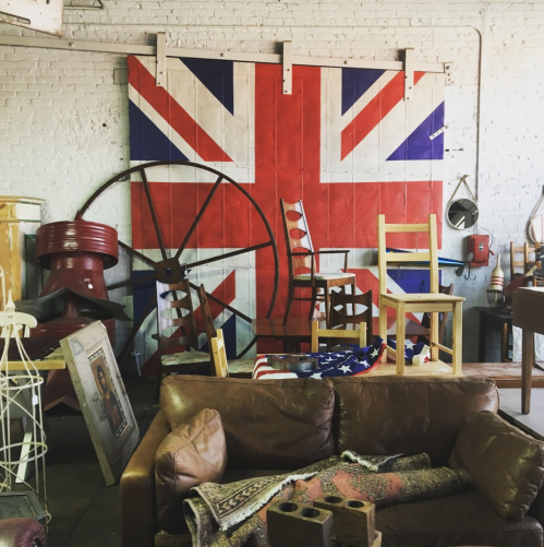 A cozy vintage shop interior featuring a Union Jack wall, wooden chairs, and various eclectic decor items.