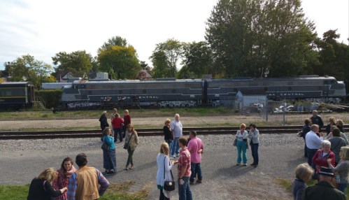 A crowd gathers near vintage trains labeled "New York Central" in a scenic outdoor setting.