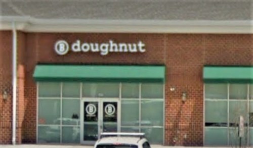A storefront with a sign that reads "doughnut" and large windows, featuring a green awning.