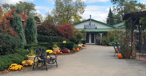 A scenic view of Becker Brewing with colorful flowers and pumpkins lining the pathway, surrounded by greenery.