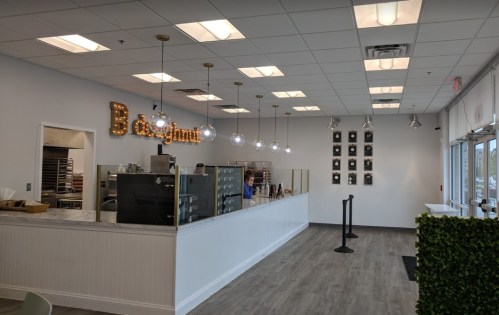 A bright, modern donut shop interior with a counter, display cases, and decorative lighting.