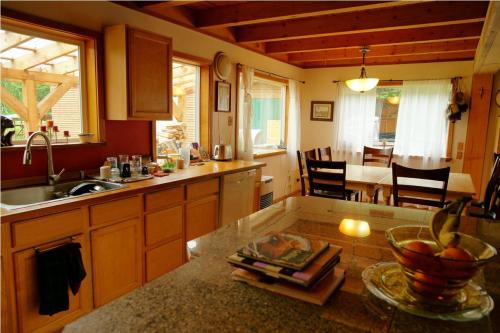 A cozy kitchen with wooden beams, a sink, and a dining area featuring a table and chairs, illuminated by natural light.