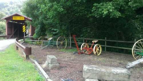 A rustic scene featuring old wooden wheels and a covered bridge surrounded by greenery.