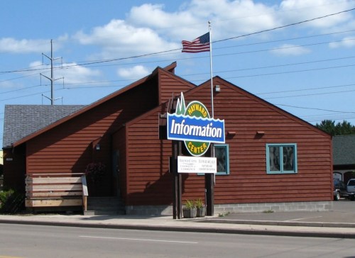 A brown wooden building with a sign reading "Information Center" and an American flag flying outside.