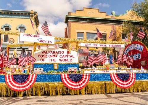 A festive parade float decorated with American flags and banners celebrating Valparaiso as the "Popcorn Capital of the World."
