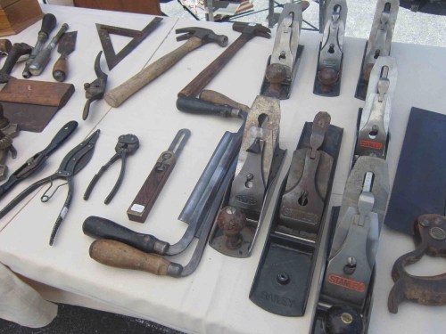 A variety of vintage woodworking tools displayed on a table, including planes, hammers, and measuring instruments.
